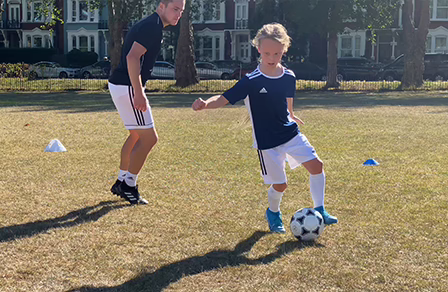 A young player and a coach take part in a fun football training session from the Family F.C. app.