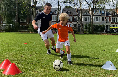 A young player and a coach take part in a head-to-head challenge from a Family F.C. session.